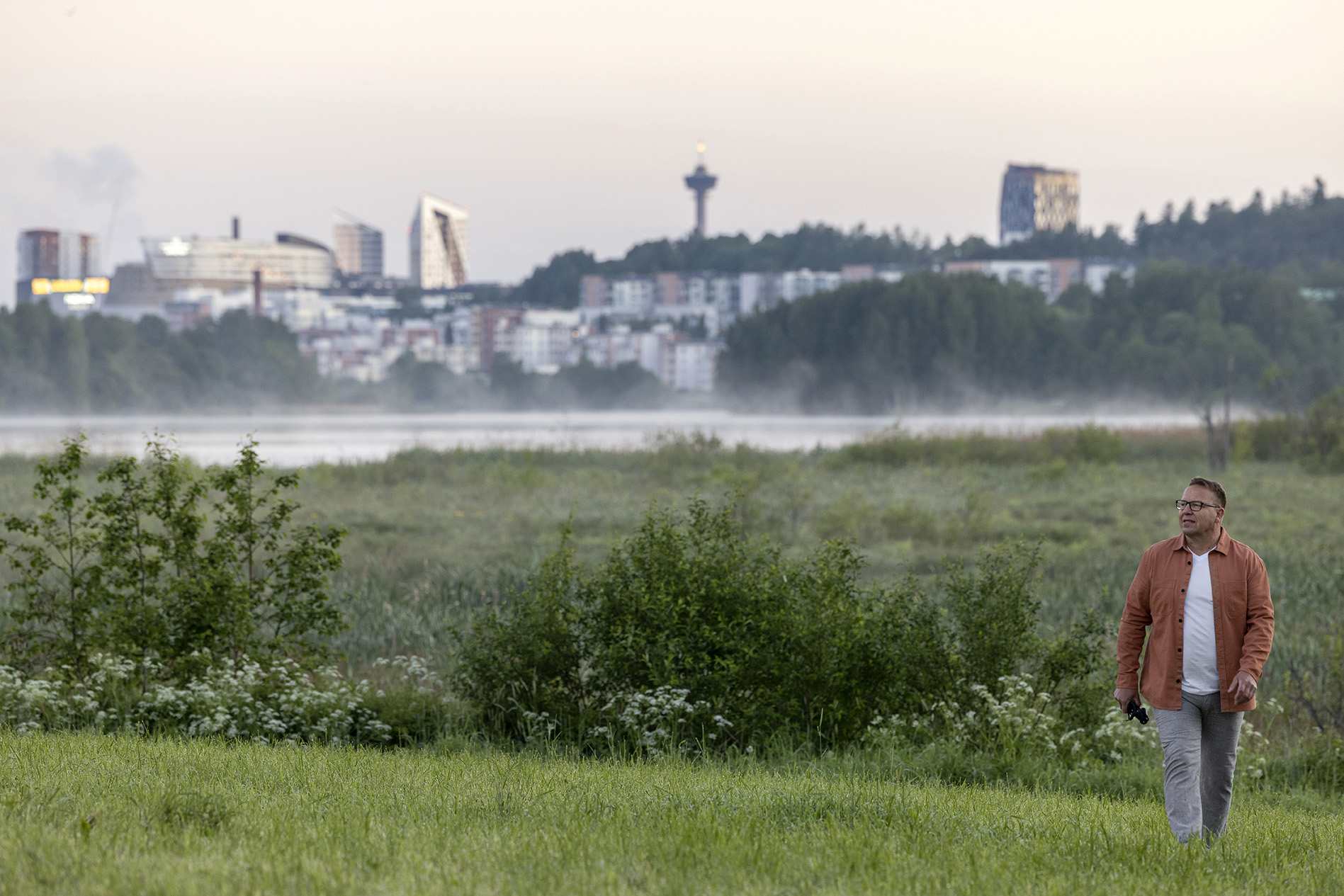 Mies kävelee pellolla taustalla kaupunkisiluetti